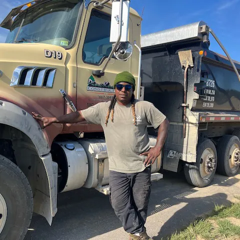 Pine Knoll Construction dump truck driver standing in front of a Pine Knoll Construction dump truck.
