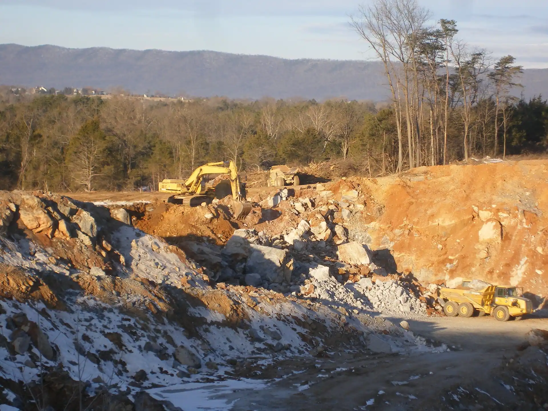 A construction site with excavators, loaders, and dump trucks completing site work and grading services.