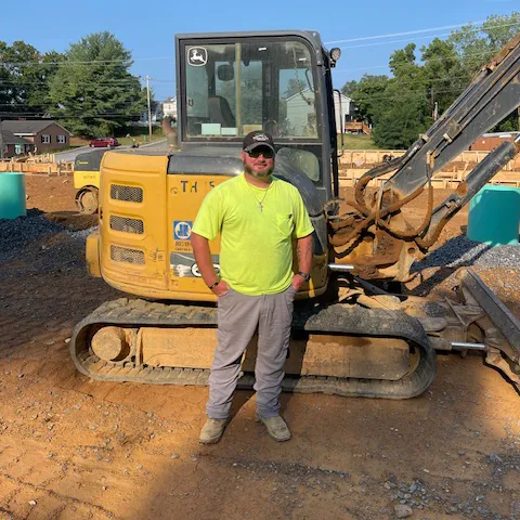 Ryan Bane standing in front of a Pine Knoll Excavator.